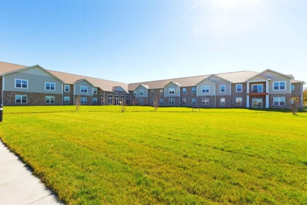 Exterior view of a senior living facility with green lawn