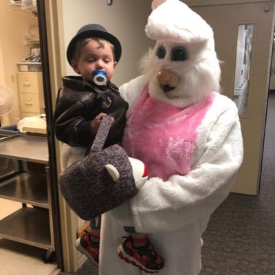 A person in a bunny costume holding a child indoors