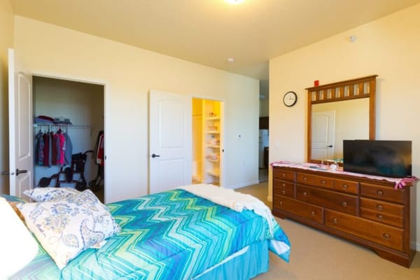 A well-furnished private resident room with a bed and dresser