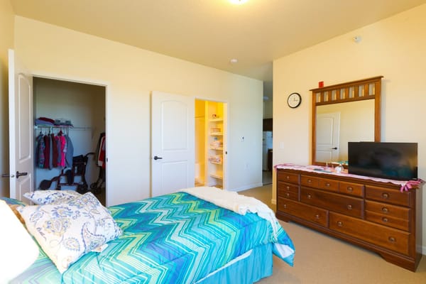 A well-furnished private resident room with a bed and dresser