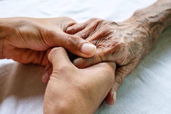 A caregiver holding the hand of a senior resident