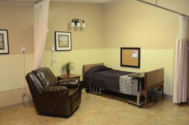 A well-furnished resident room with a recliner and bed