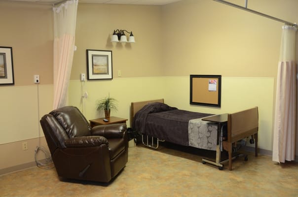 A well-furnished resident room with a recliner and bed