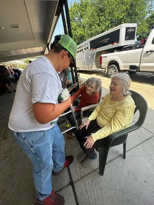 A child showing a rabbit to two smiling elderly women