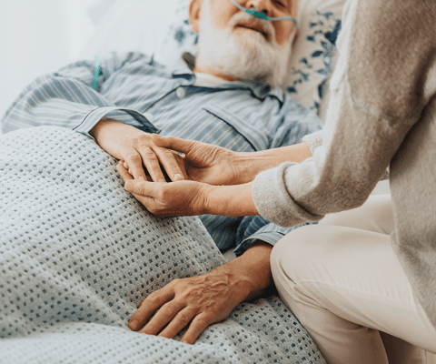 Caregiver holding the hand of a resident in bed