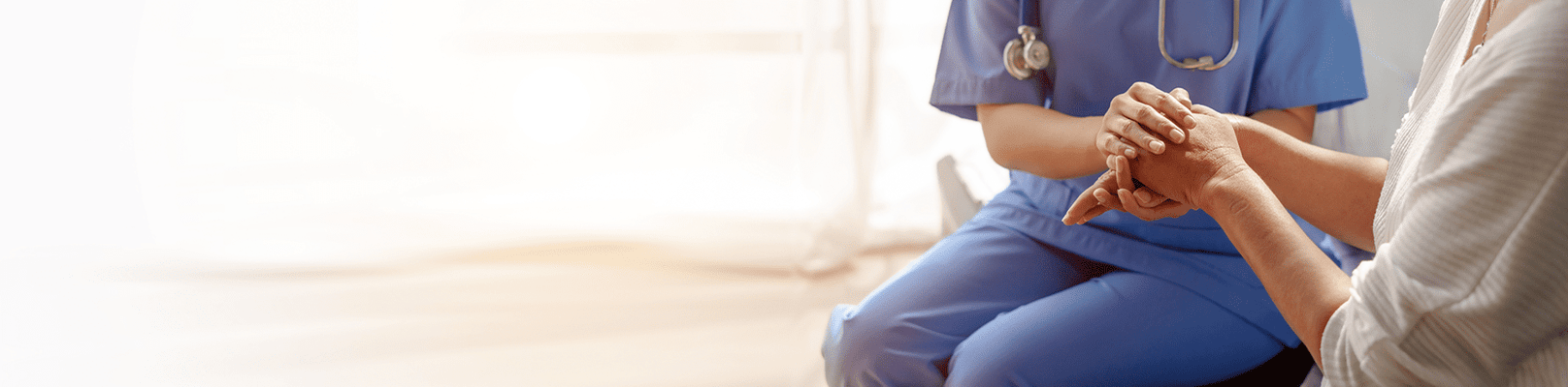 Healthcare professional holding a resident's hand