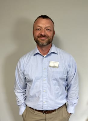 A staff member smiling in a collared shirt