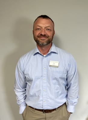 A staff member smiling in a collared shirt