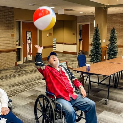 Resident playing with a beach ball in an activity room