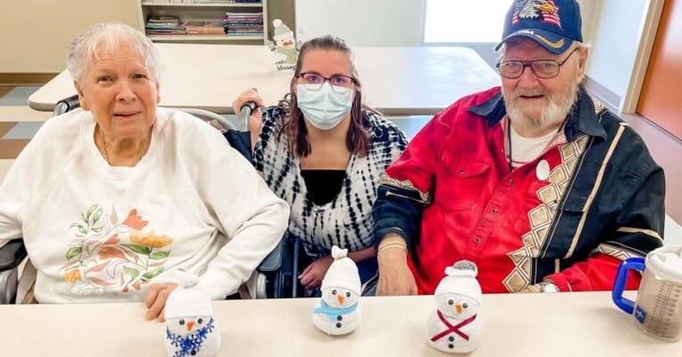 Residents and a staff member with snowman crafts