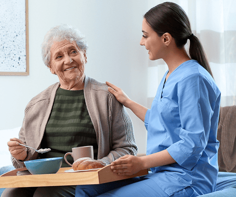 Resident enjoying a meal with caregiver in a cozy room