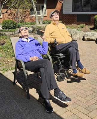 Two residents enjoying the sun in a garden area