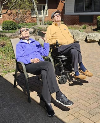 Two residents enjoying the sun in a garden area