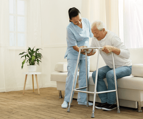 Nurse assisting an elderly man with a walker in a cozy room