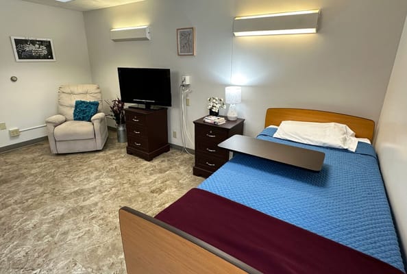 A private resident room with a bed and chair