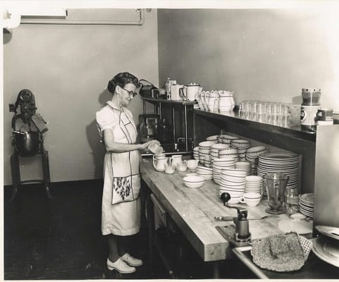 A staff member setting tables in a kitchen area