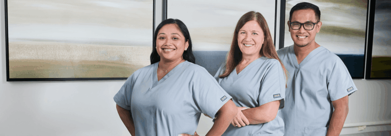 Three staff members posing in a well-lit room