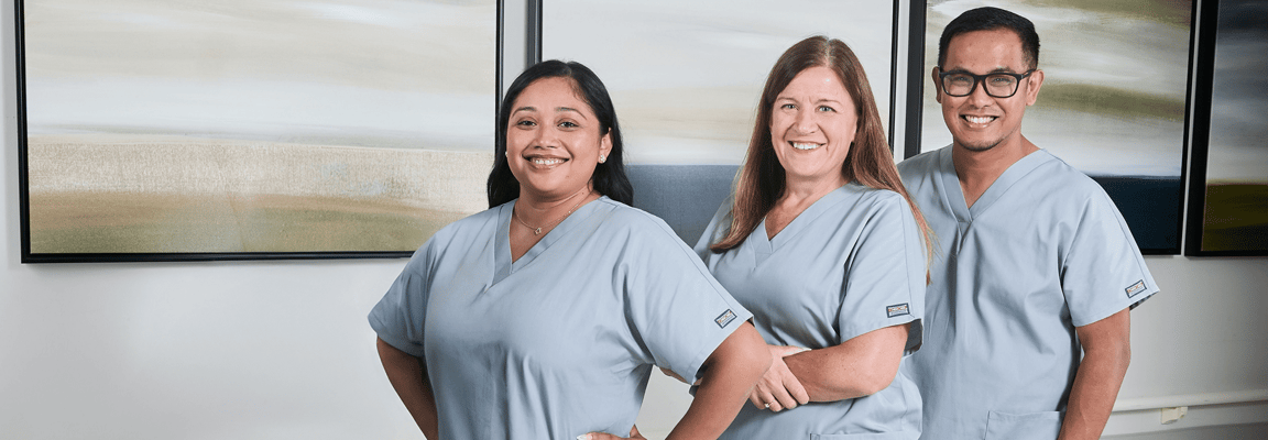 Three staff members posing in a well-lit room