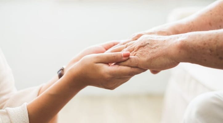 Close-up of a younger and older person's hands holding each other