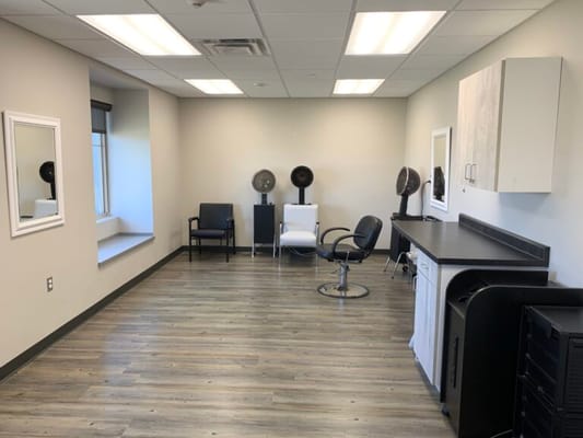 Bright and clean hair salon area with chairs and mirrors