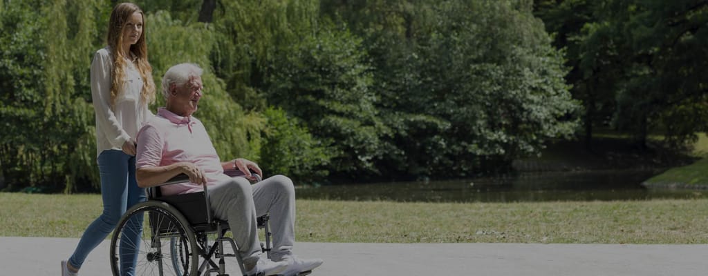 A caregiver assisting a resident in a wheelchair outdoors