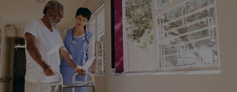 A nurse assisting an elderly man with a walker