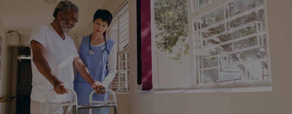 A nurse assisting an elderly man with a walker
