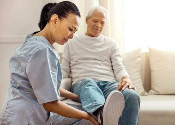 A caregiver assisting a senior man with his leg