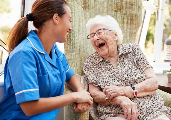 Caregiver and resident laughing together in a cozy setting