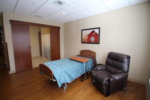 A private resident room with a bed and recliner chair