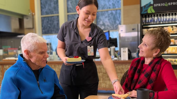 Staff serving dessert to residents in a dining area