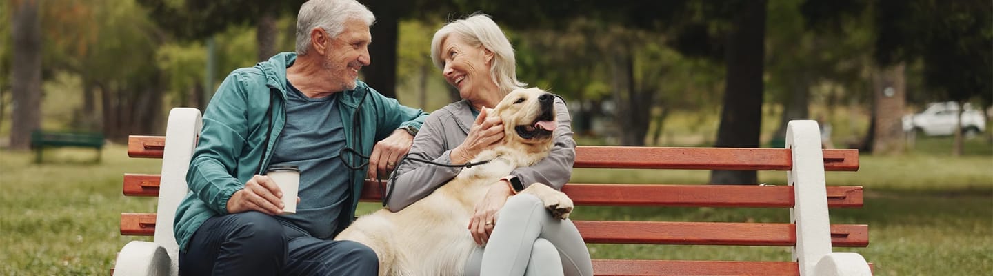 Seniors enjoying time together on a park bench with a dog