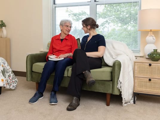 A resident and staff member conversing on a couch