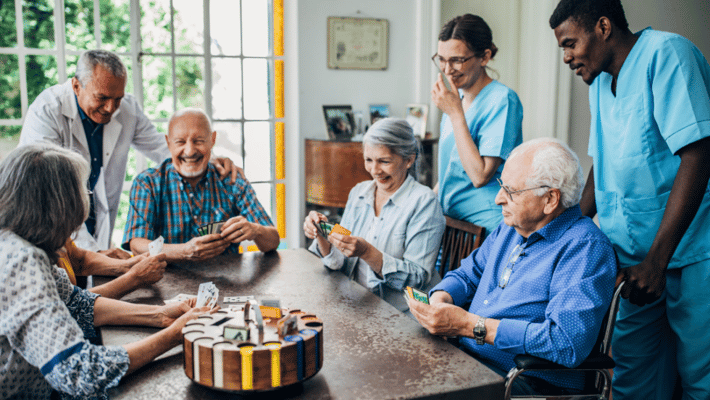Residents engaged in a card game with attentive staff