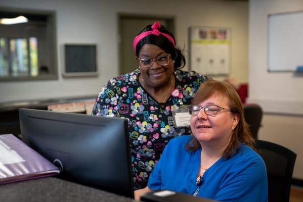 Staff assisting residents at a computer station