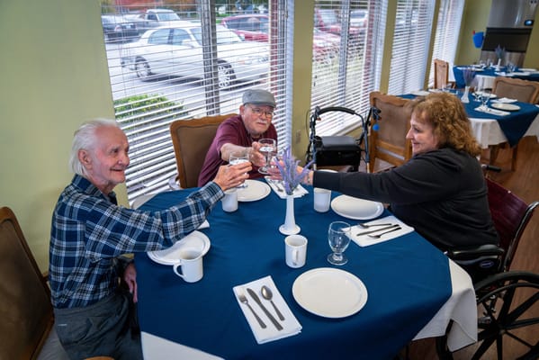 Residents toasting at a dining table in the facility