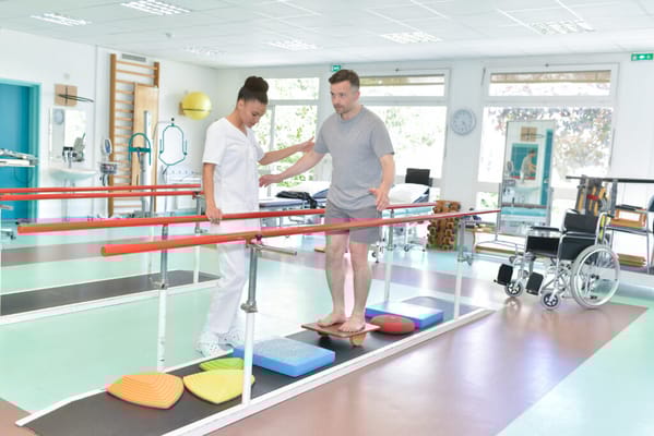 Resident practicing balance with staff assistance in therapy room