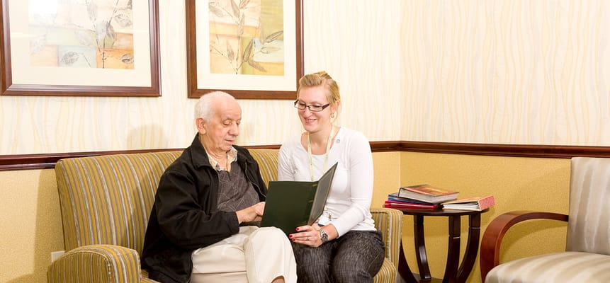A staff member reading with a resident in a cozy lounge