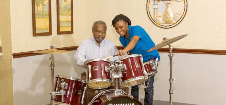 Resident and staff member playing drums together