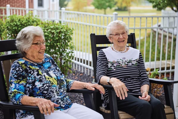 Two senior women enjoying outdoor rocking chairs