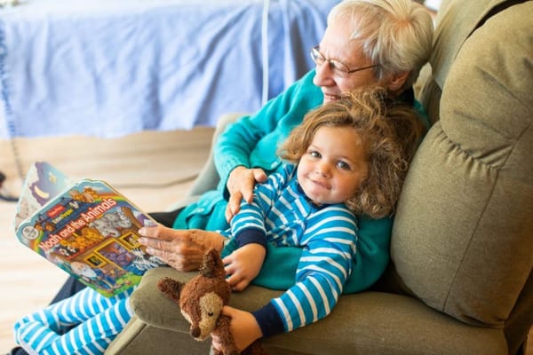 An elder reading with a young child in a cozy setting