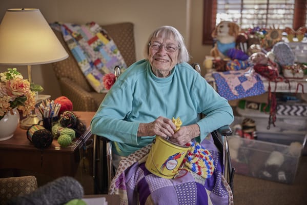 Resident smiling while crafting in a cozy room