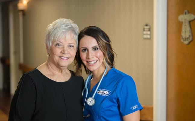 A resident and nurse smiling together in a hallway