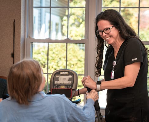 Staff assisting a resident with exercise equipment