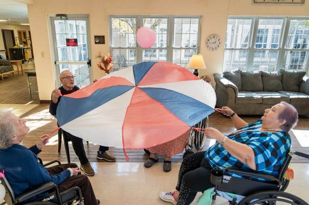 Residents playing with a colorful parachute in a common area