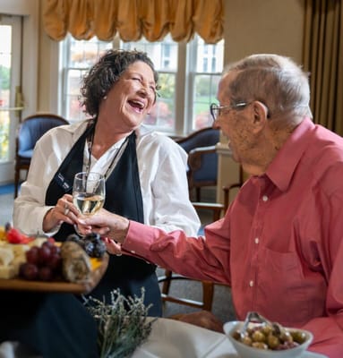 A resident enjoying a drink with staff in the dining area