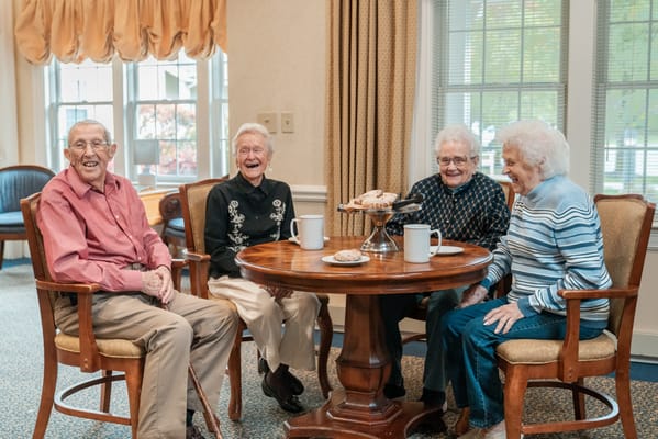 Four residents laughing around a table in a common area
