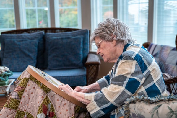 An elderly woman engaged in a craft activity indoors