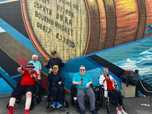 Residents enjoying a sunny day outdoors with a mural backdrop