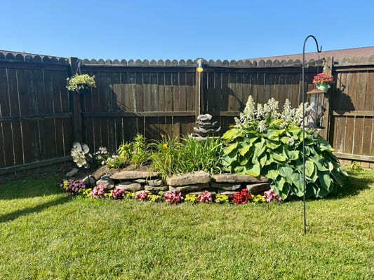 A beautifully landscaped garden with flowers and a stone feature